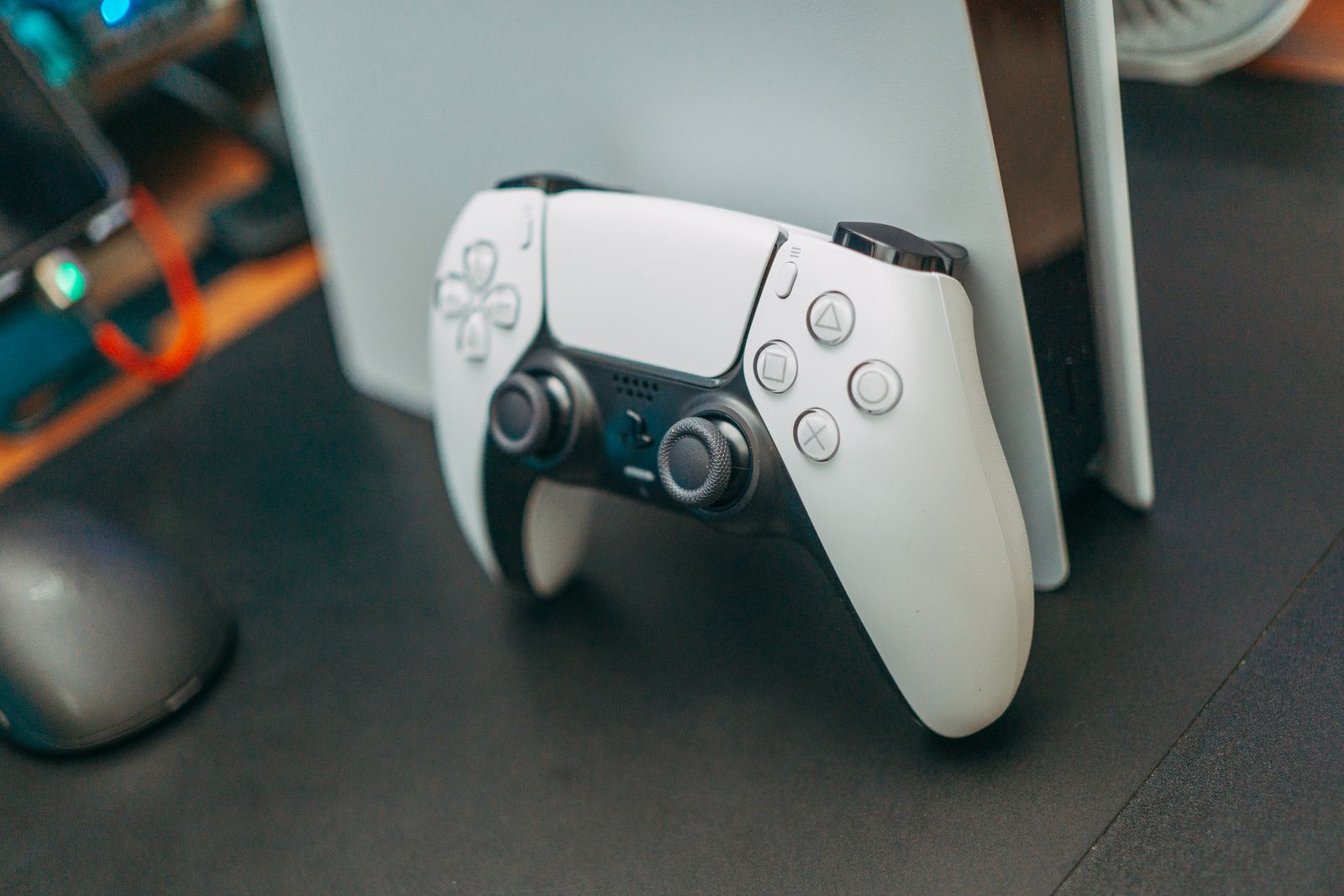 White DualSense controller leaning against its console on a desk.